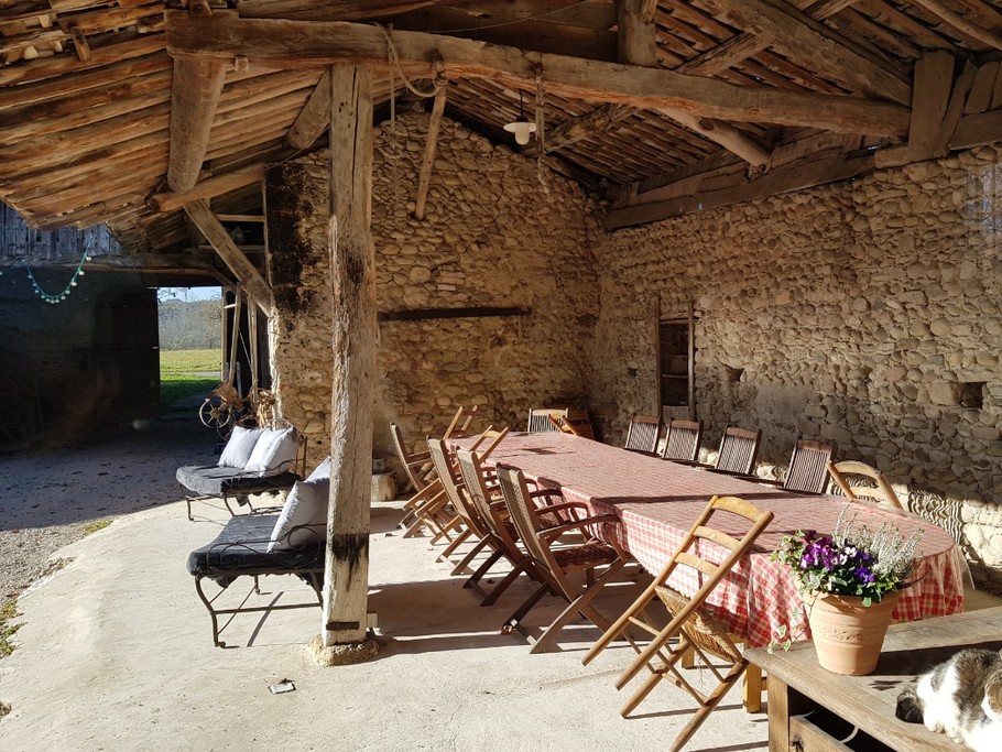 Sous le préau, la grande table extérieure mais protégée du soleil et de la pluie pour partager l'apéritif ou les repas