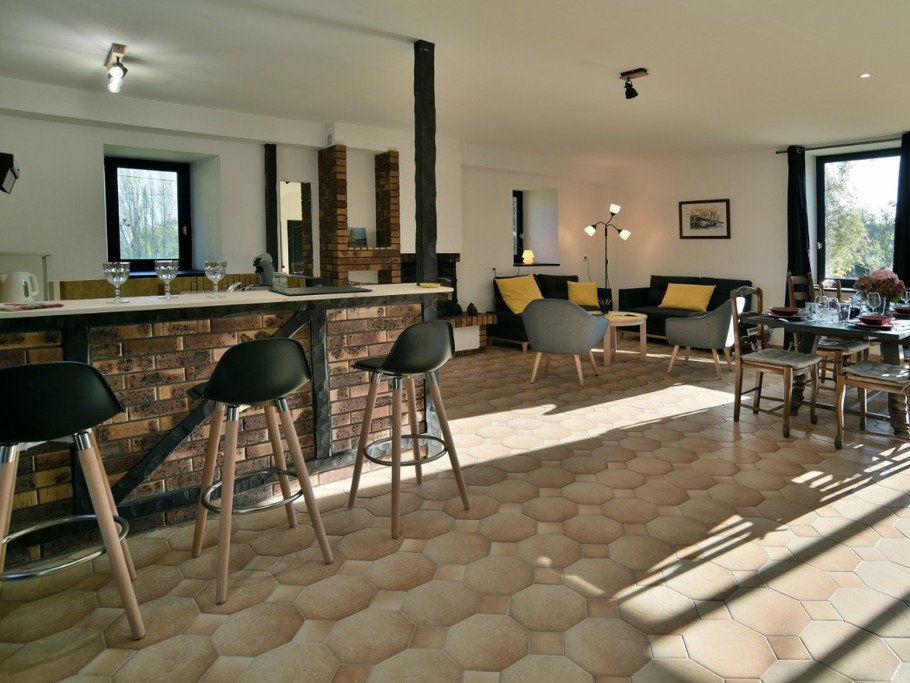 Grande pièce de vie au RDC avec coin cuisine ouverte, toute équipée et comptoir, coin salon avec cheminée, coin séjour.