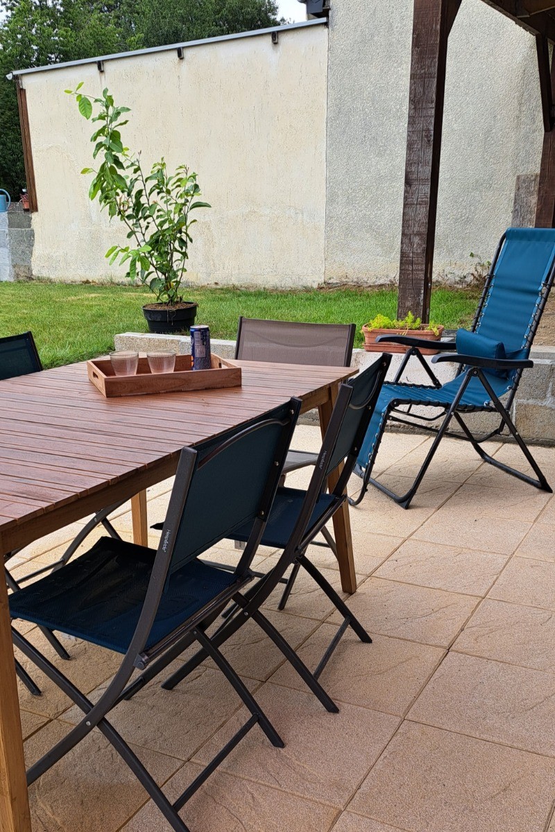 Terrasse ombragée et terrain clos avec pelouse et jeux pour enfants.