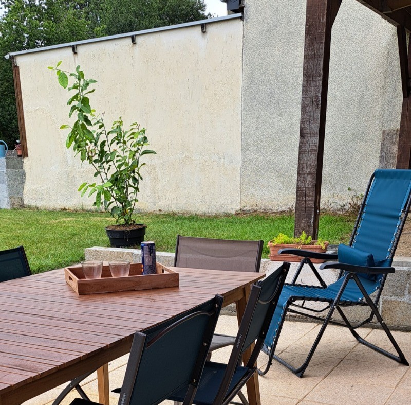 Terrasse ombragée et terrain clos avec pelouse et jeux pour enfants.