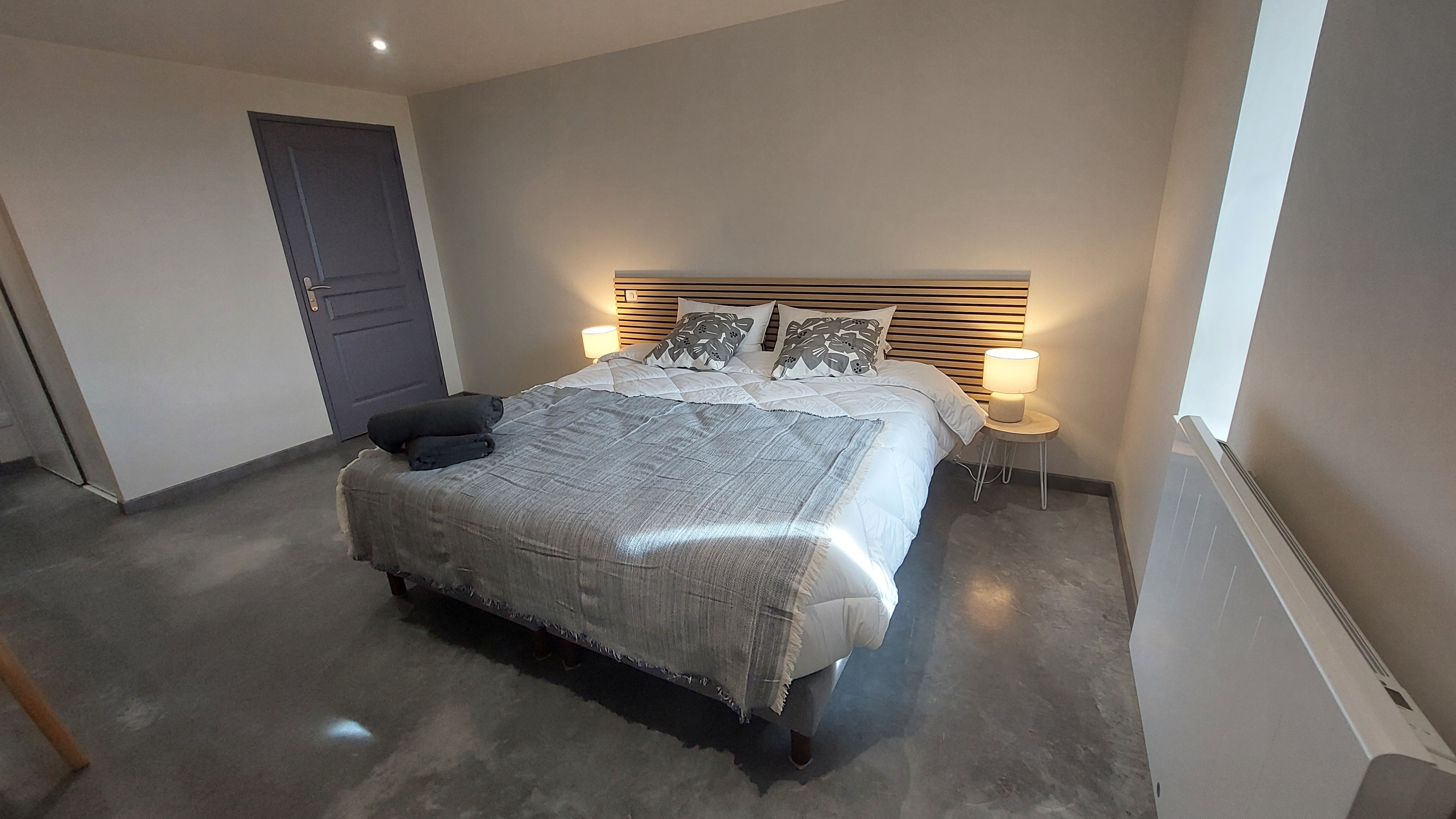 Chambre grise PMR avec lit double modulable, salle de bain adaptée et accès facilité