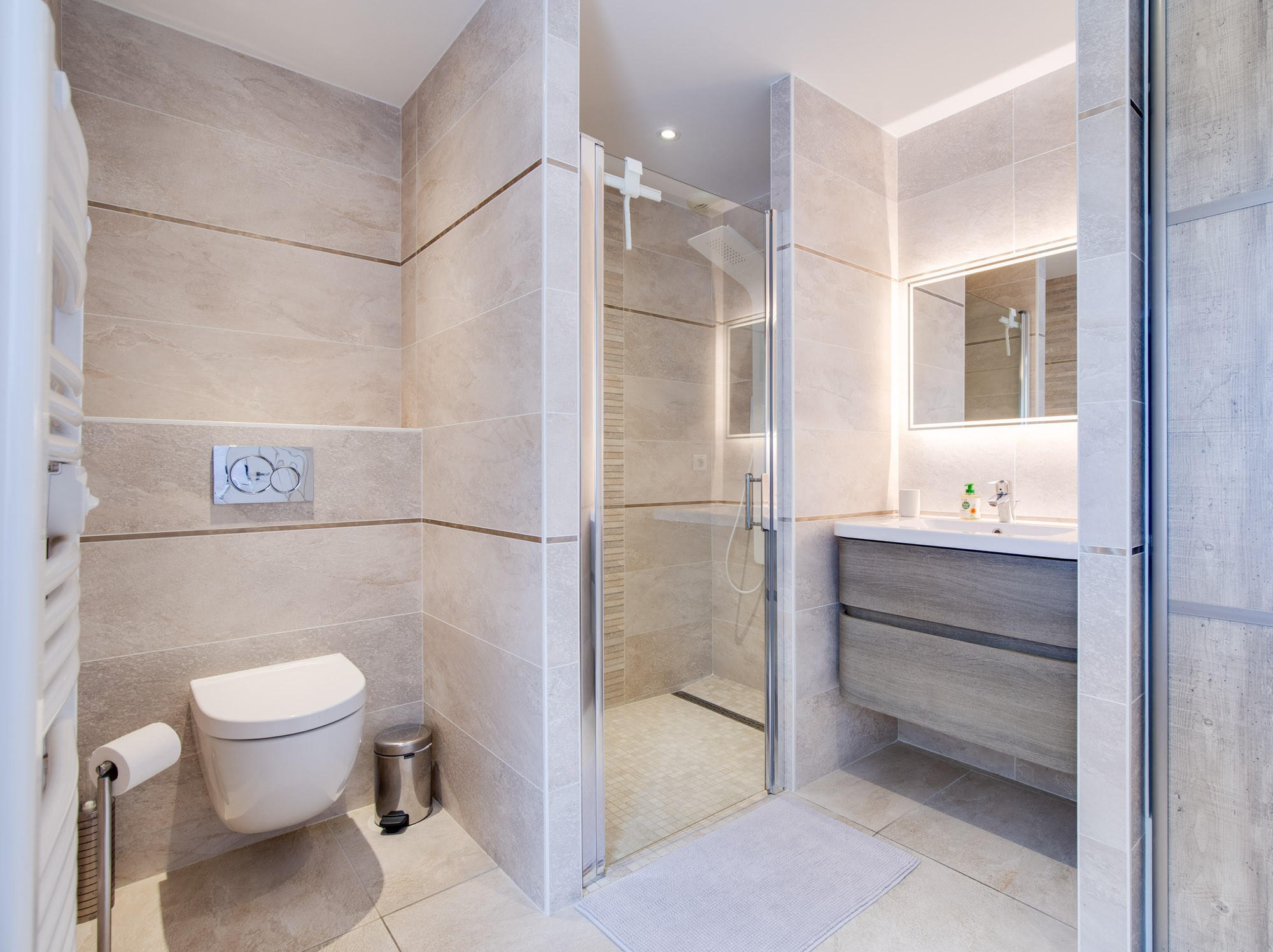 Salle de bain avec douche italienne, colonne de douche hydromassante et WC.