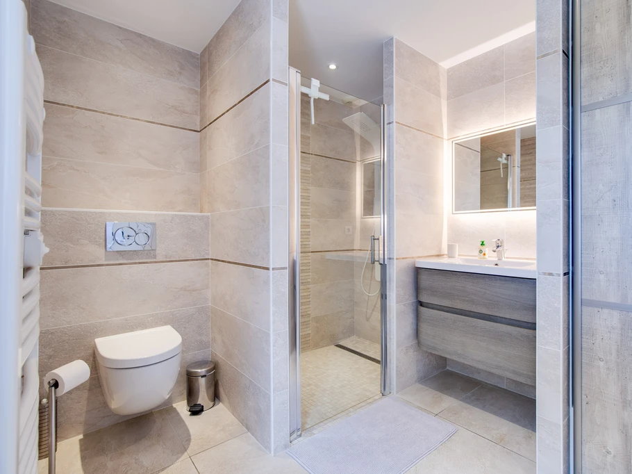 Salle de bain avec douche italienne, colonne de douche hydromassante et WC.