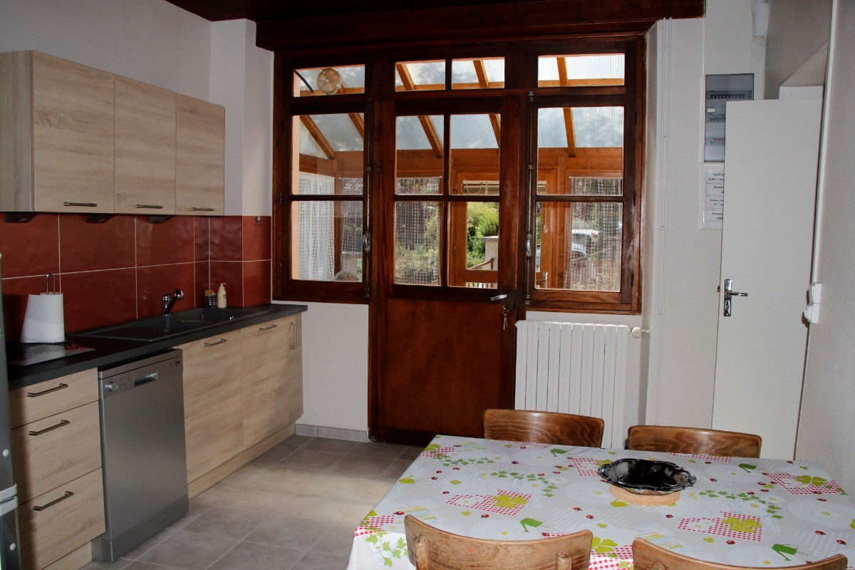 Cuisine lumineuse avec porte donnant sur le devant de la maison, facilitant l’accès à la terrasse.