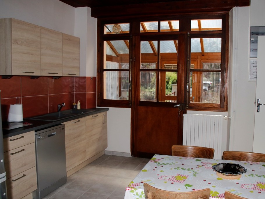 Cuisine lumineuse avec porte donnant sur le devant de la maison, facilitant l’accès à la terrasse.