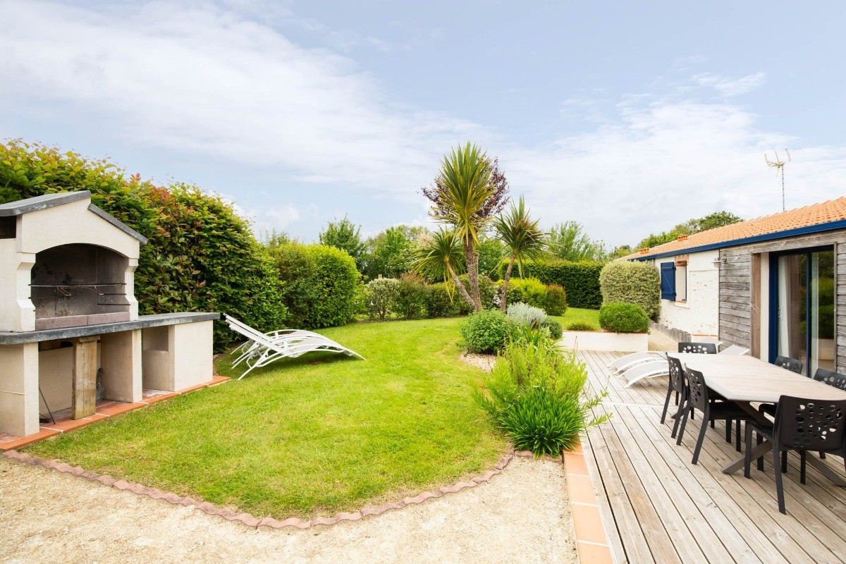 Jardin privatif avec terrasse, salon de jardin, transats, parasol, barbecue et fils à linge.