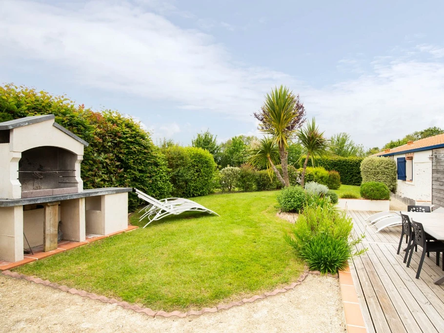 Jardin privatif avec terrasse, salon de jardin, transats, parasol, barbecue et fils à linge.