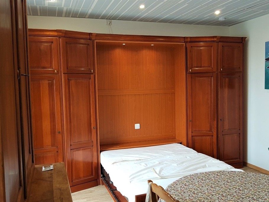 Le coin nuit est un lit confortable pour 2 personnes (140x190cm), élégamment dissimulé dans un dressing le jour.  
Crédits photos : Clévacances 35