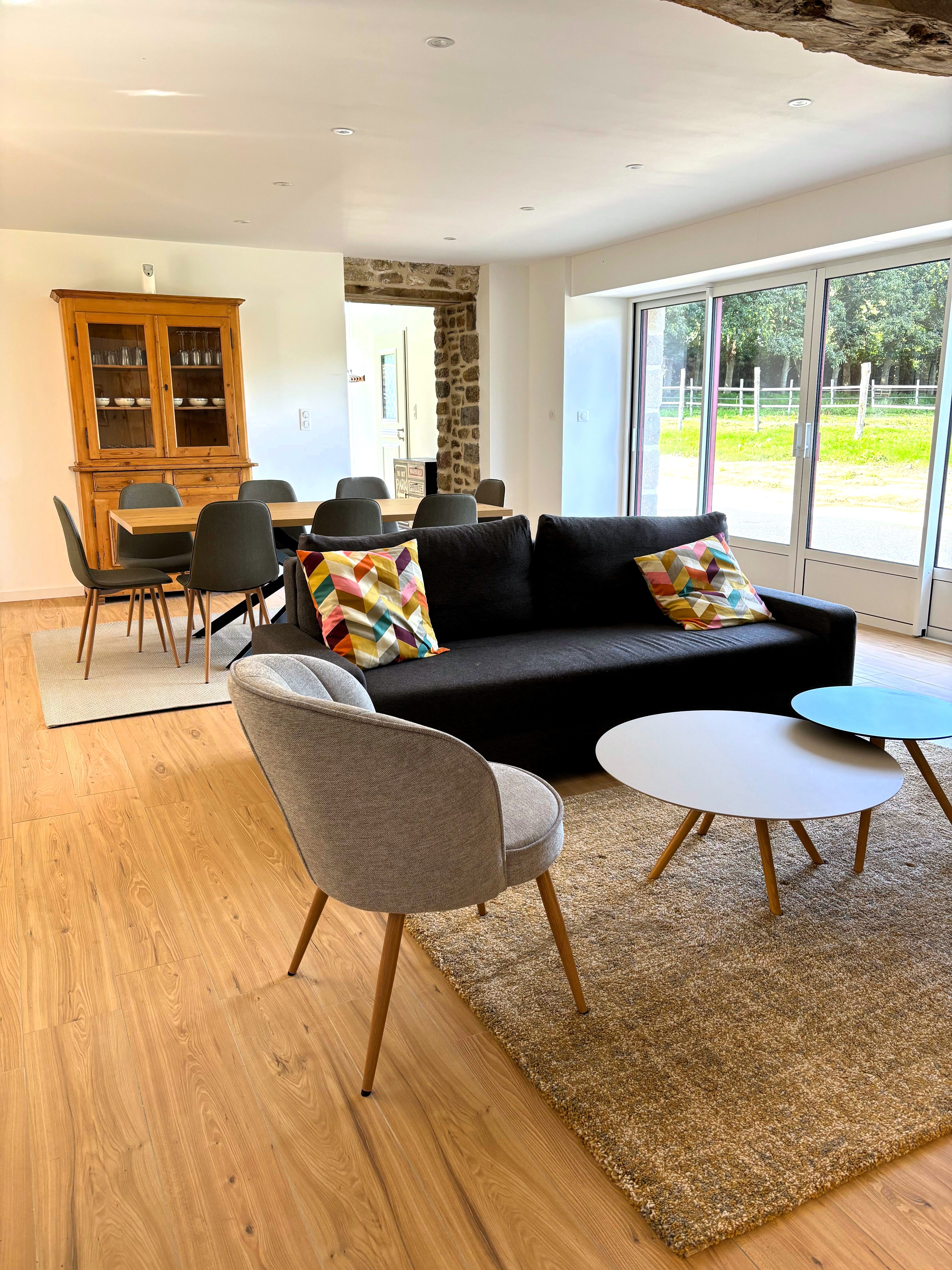Grande pièce de vie avec salon (poêle à bois, smart TV), séjour et cuisine ouverte parfaitement équipée.