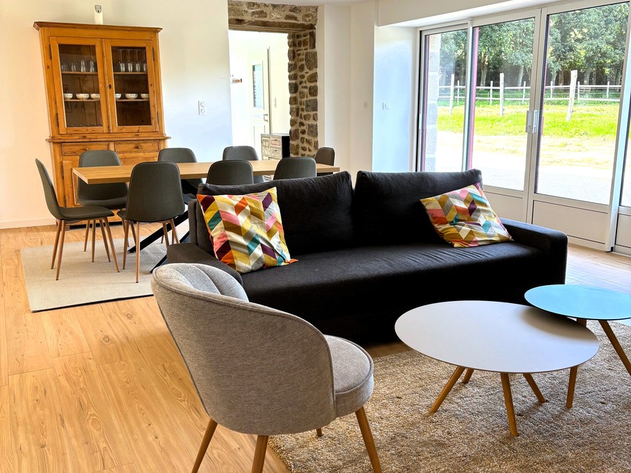 Grande pièce de vie avec salon (poêle à bois, smart TV), séjour et cuisine ouverte parfaitement équipée.