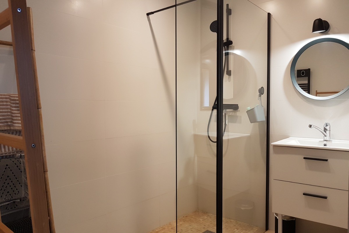 Salle d'eau communicante avec douche à l'italienne grande dimension, meuble vasque et rangements.