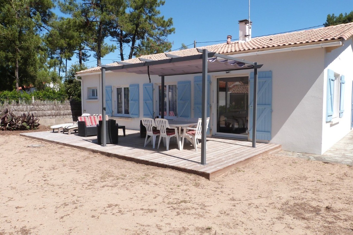 Jardin sablonneux avec salon de jardin et pergola