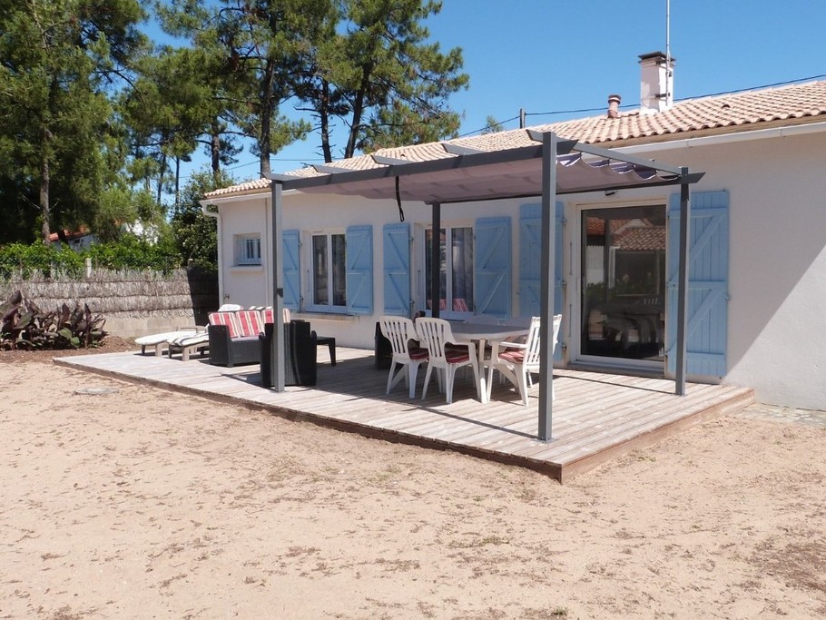 Jardin sablonneux avec salon de jardin et pergola