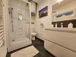 Salle d'eau avec meuble vasque, radiateur sèche serviette, douche grande dimension et WC, attenants à la chambre
