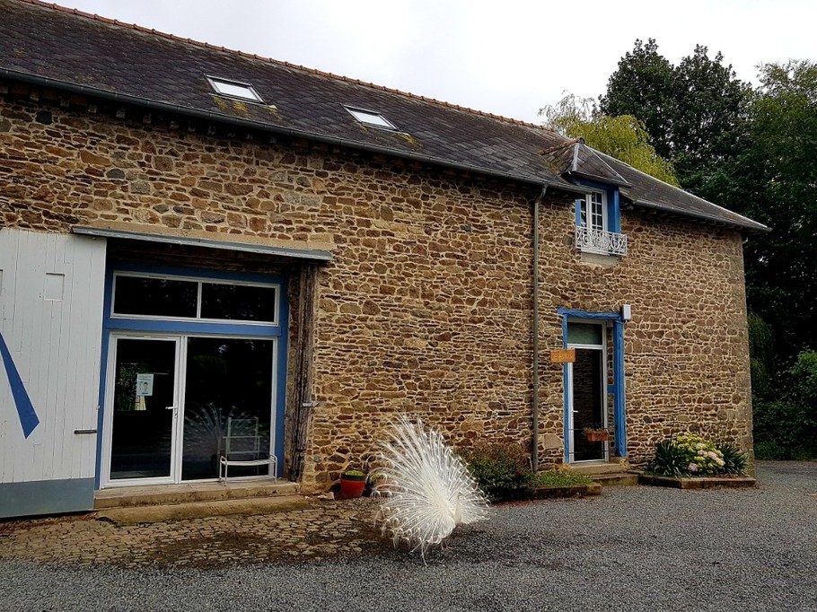 La façade du gîte, une maison en pierres de pays. L'entrée se situe à l'arrière. A gauche de la photo, le local piscine intérieure, commune à une autre gîte.