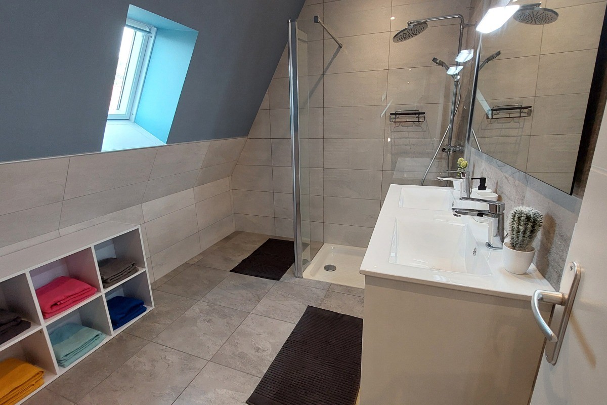 Grande salle d'eau moderne du gîte La Petite Maison avec double vasque et douche à l'italienne.