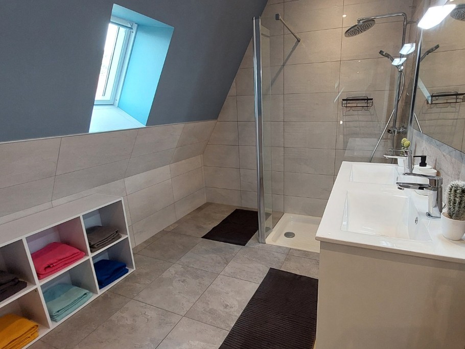 Grande salle d'eau moderne du gîte La Petite Maison avec double vasque et douche à l'italienne.