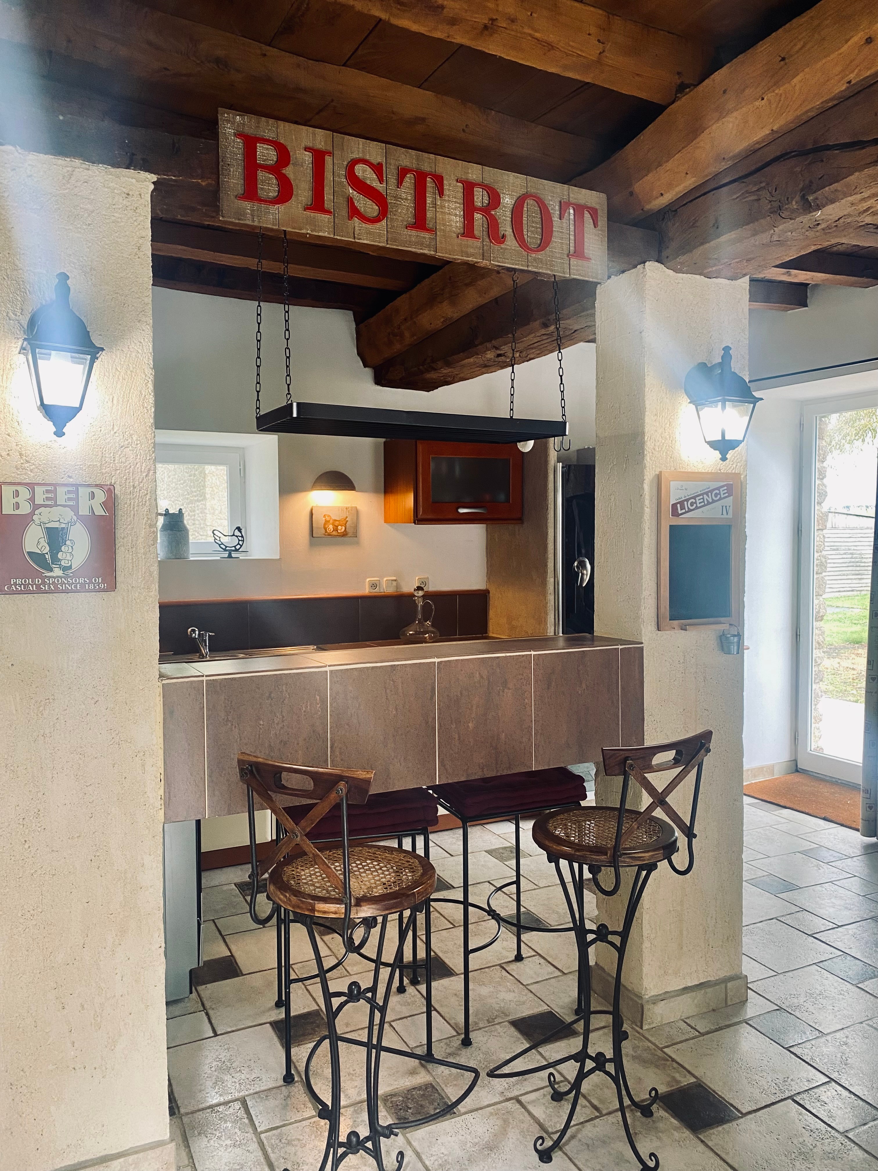 Grande pièce de vie au rez-de-chaussée avec espace cuisine toute aménagée et son mini bar, espace séjour, espace (vrai) bureau, et espace salon avec canapé en cuir, poêle à bois et TV.