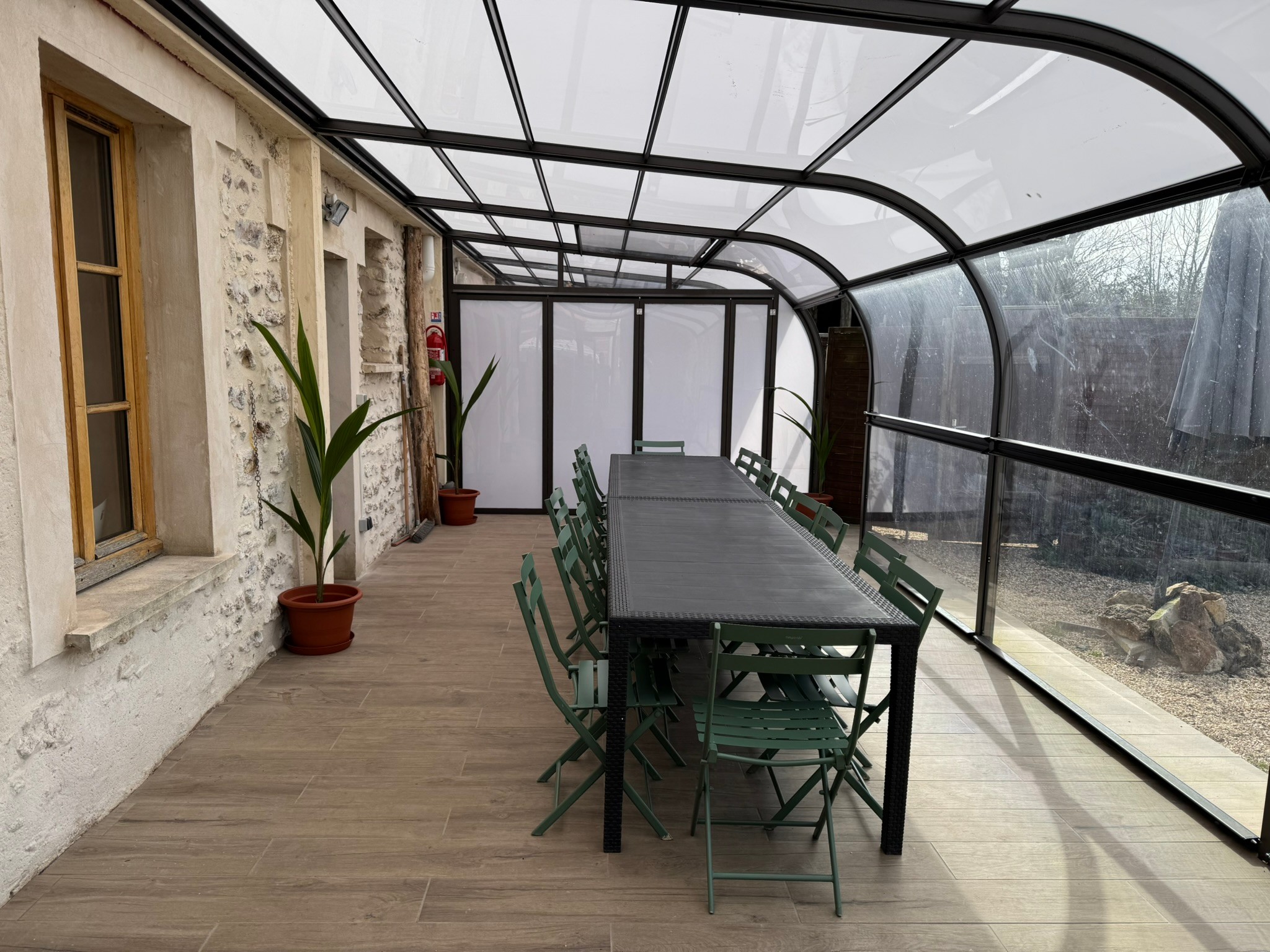 Véranda entièrement découvrable (pour obtenir une terrasse couverte) de 30m2. Plantes d'agrément. Brasseurs d'air en été