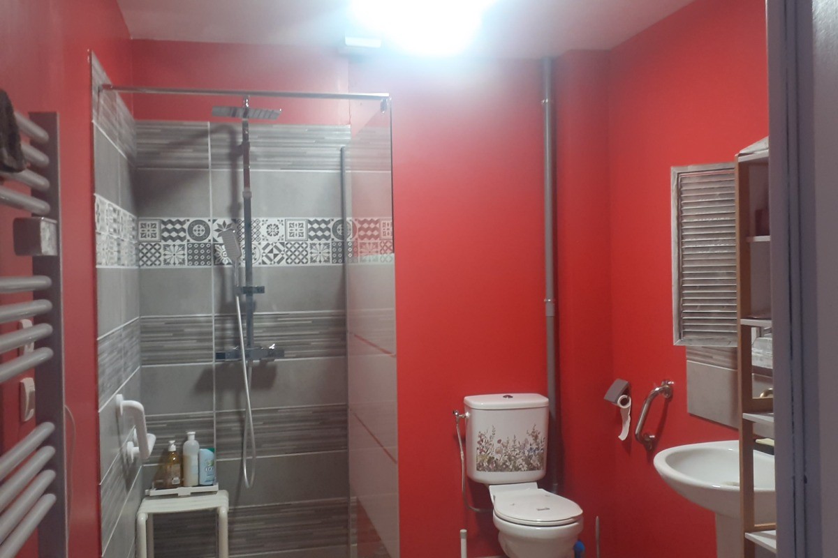 salle de bains avec douche italienne accessible aux fauteuils et barre d'appui.