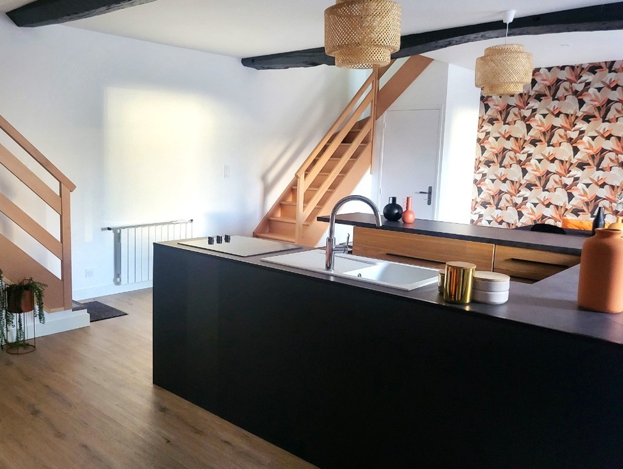 Pièce de vie au rez-de-chaussée avec sa cuisine ouverte, un coin séjour, un coin salon. 2 escaliers de part et d'autres desservent les 2 chambres.