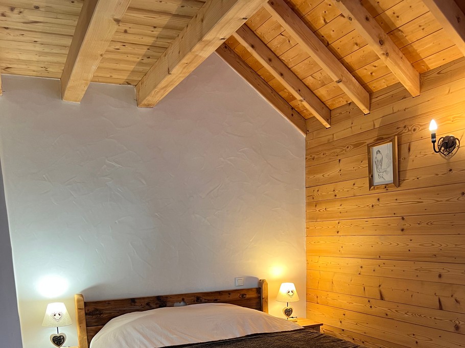 Chambre 2 avec un lit de 160x200 cm, un placard intégré et un balcon offrant une vue sur les pistes de ski et les montagnes.