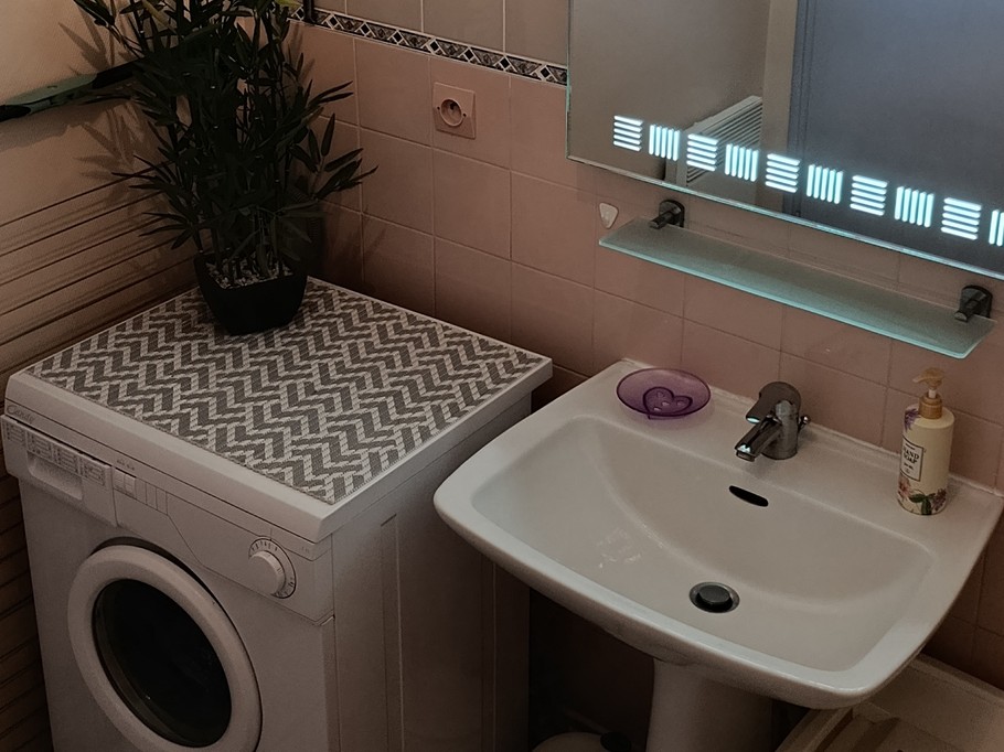 The bathroom with a bath, washing machine and storage shelves
