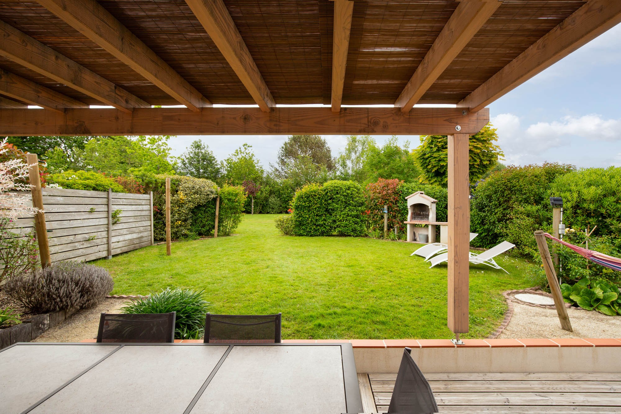 Jardin privatif avec pergola, hamac, salon de jardin, bain de soleil, barbecue et fils à linge.