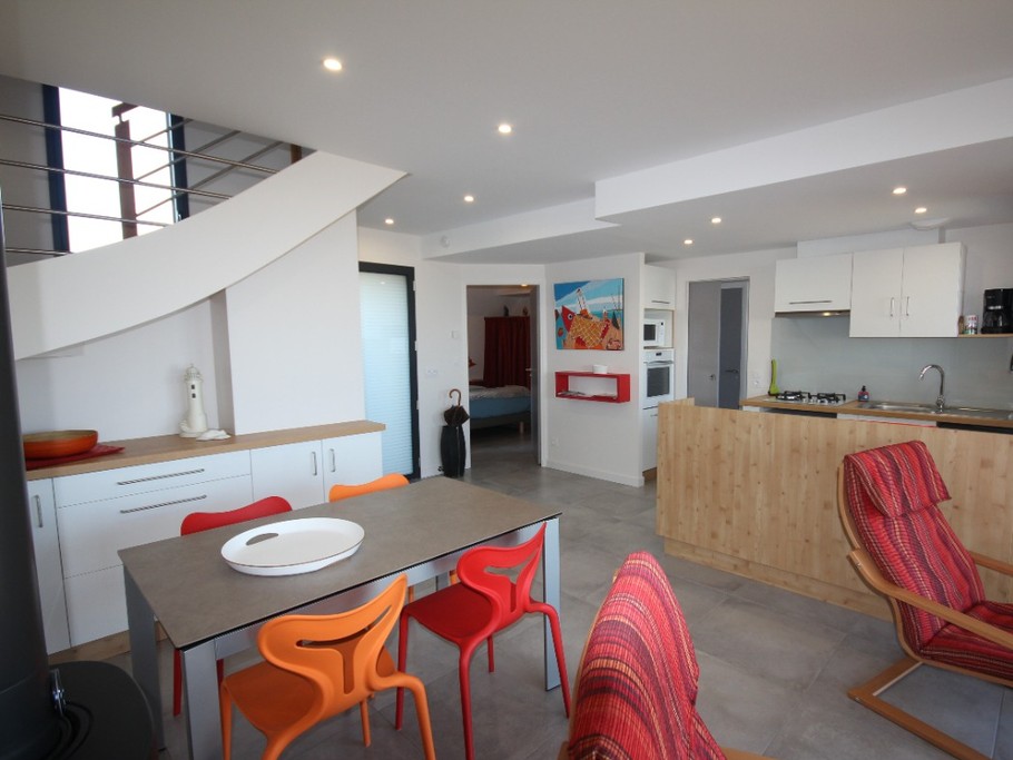 Pièce principale, cuisine ouverte, coin repas et salon. En face entrée chambre du rdc, à droite après la colonne four/micro onde c'est la porte de la lingerie avec cabinet de toilette et w.c; passage aussi pour sortir et rentrer de la plage avec grand bac