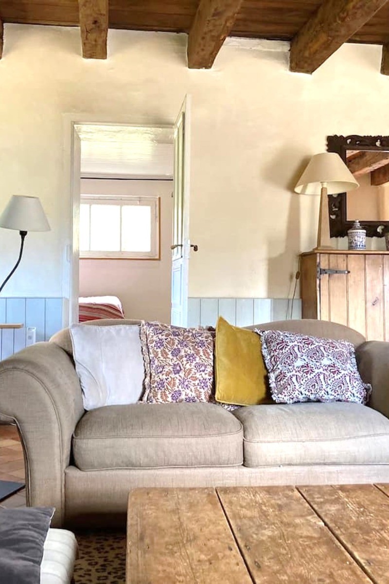 Grand salon chaleureux avec poutres apparentes et cheminée d'apparat. En enfilade, entrée, salle de billard et séjour / cuisine. 
Crédits photo :  Mégane ARNAL