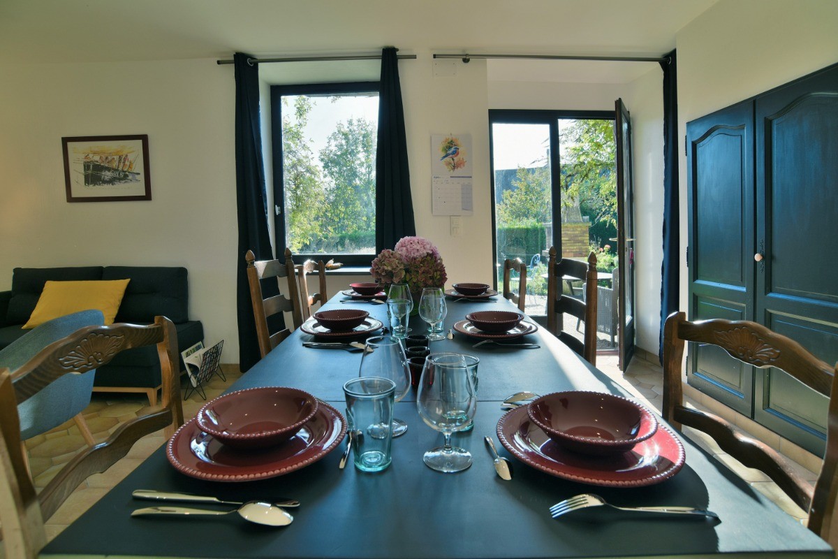 Coin repas spacieux avec baie vitrée donnant sur le jardin et la terrasse attenante.