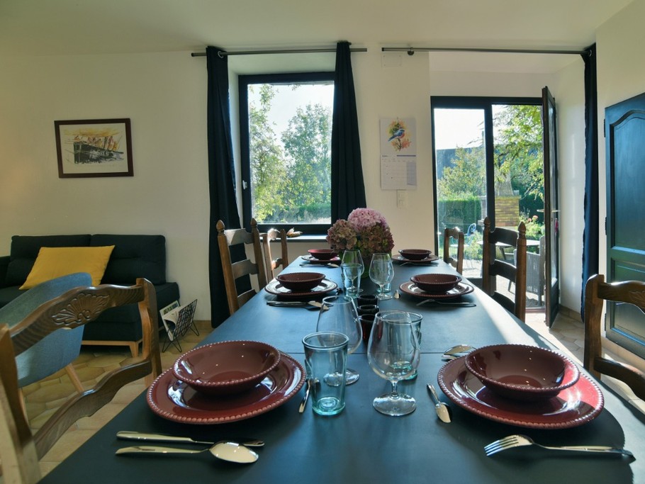 Coin repas spacieux avec baie vitrée donnant sur le jardin et la terrasse attenante.