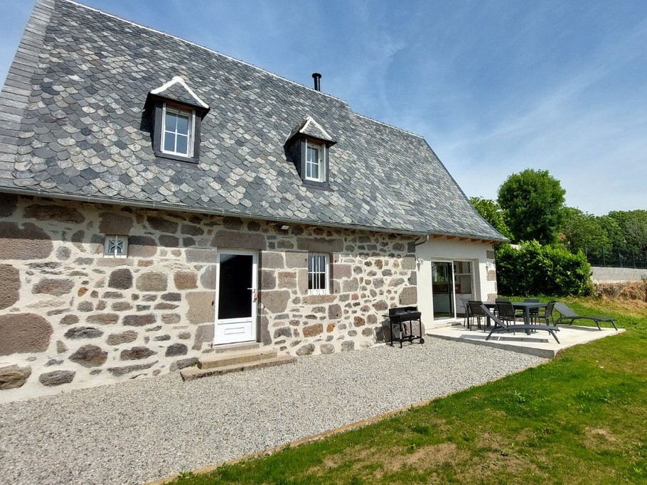 Terrasse extérieure du gîte La Petite Maison avec salon de jardin et transats, parfait pour se détendre sous le soleil du Cantal.