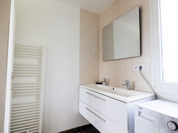 Salle d'eau avec douche grande dimension, double vasque et machine à laver