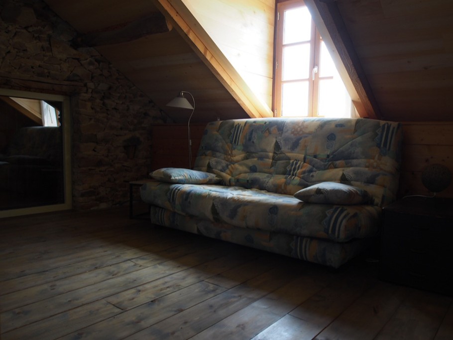 La mezzanine, coin détente et lecture avec un canapé convertible.