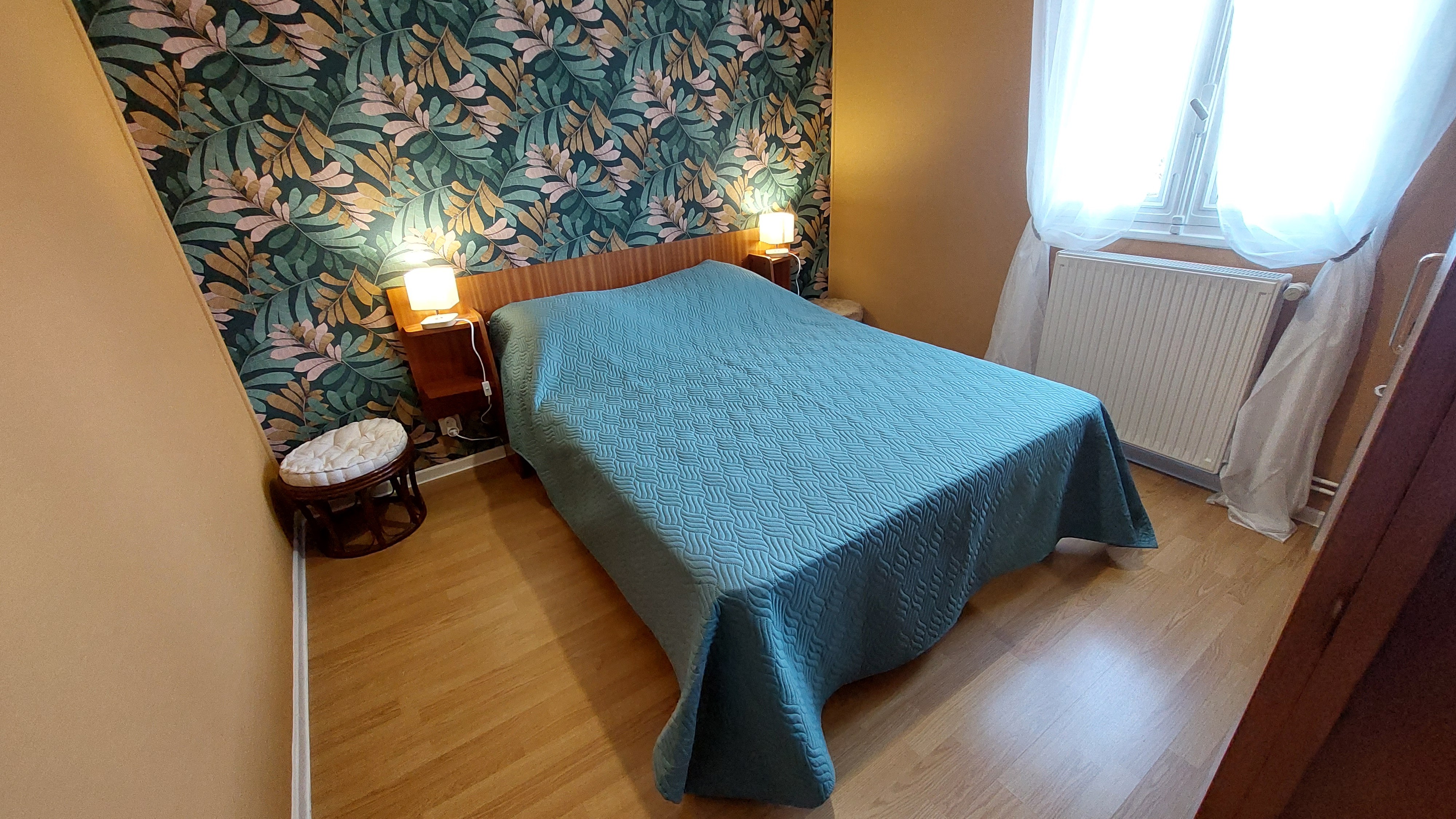 Chambre avec lit double et décoration végétale dans un gîte du Cantal