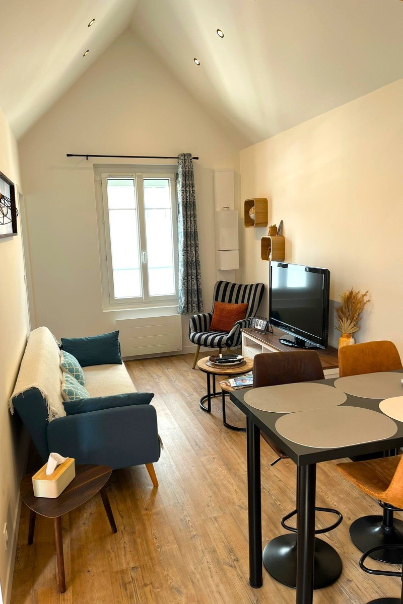 Pièce de vie spacieuse avec une belle hauteur sous plafond. Coin cuisine et coin salon.