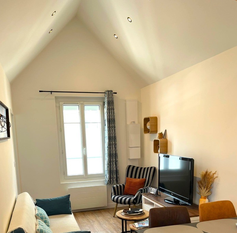 Pièce de vie spacieuse avec une belle hauteur sous plafond. Coin cuisine et coin salon.