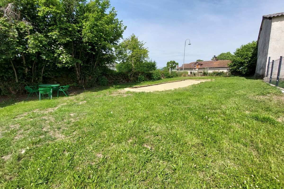 Terrain de pétanque ensoleillé dans le jardin du gîte La Petite Maison à Saint-Étienne-de-Carlat.