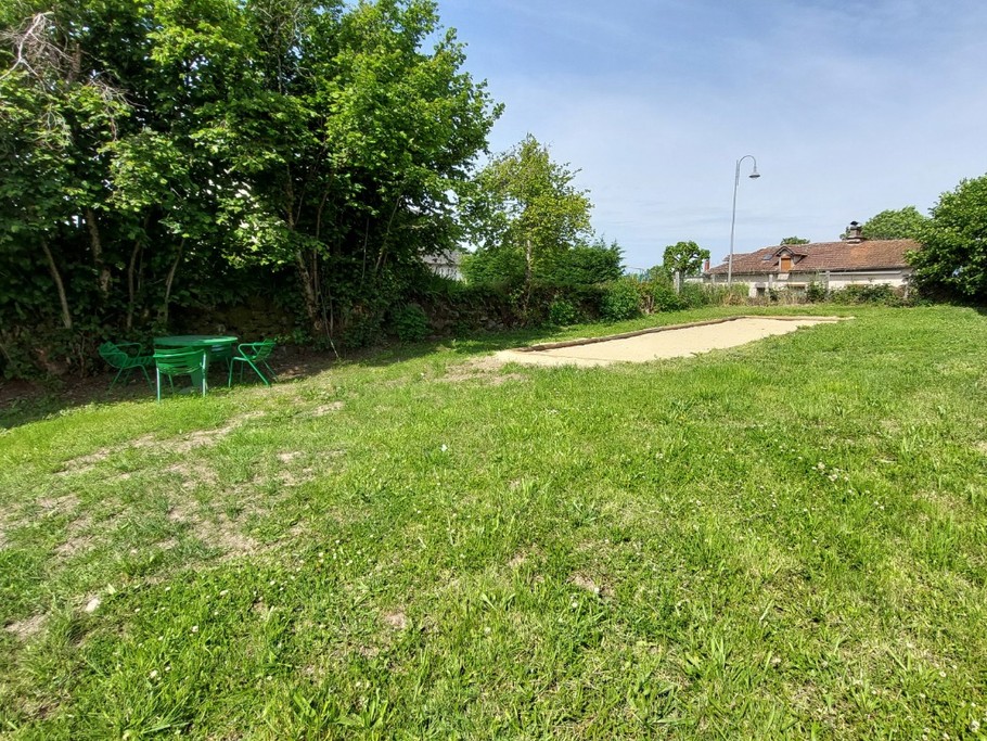 Terrain de pétanque ensoleillé dans le jardin du gîte La Petite Maison à Saint-Étienne-de-Carlat.
