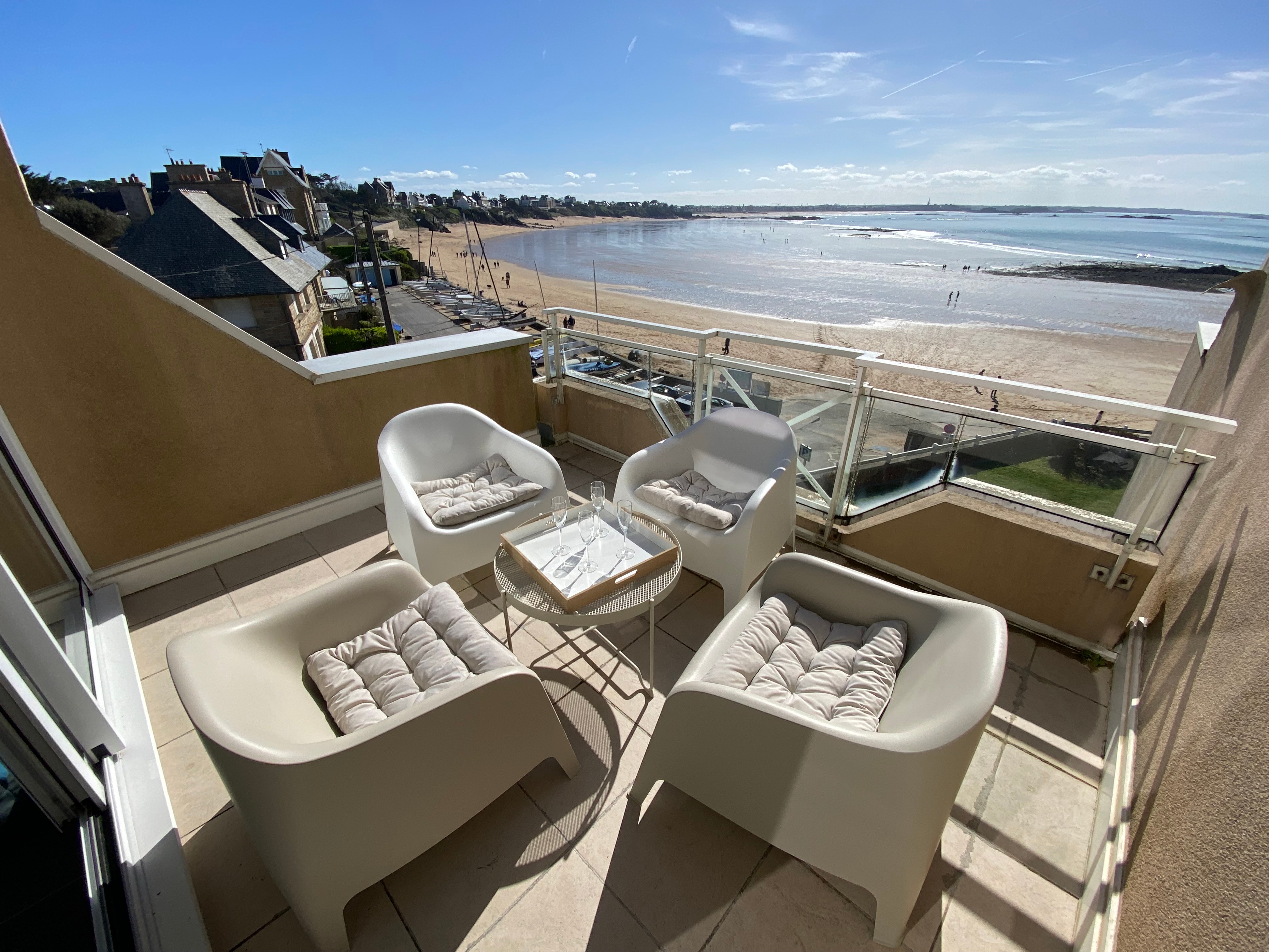 Terrasse orientée Sud-Ouest avec vue mer panoramique, avec salon de jardin et parasol d'ombrage.