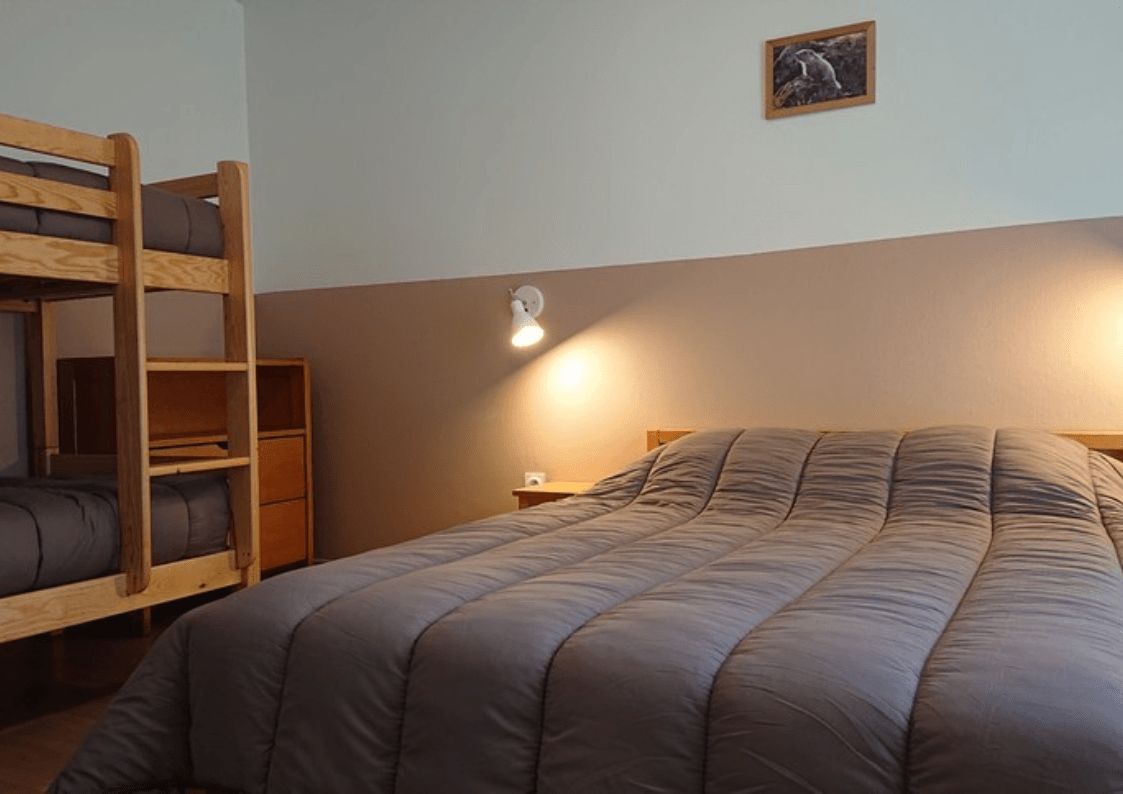 Chambre : Chambre du gîte avec un lit double et deux lits superposés, adaptée pour accueillir jusqu'à 4 personnes.