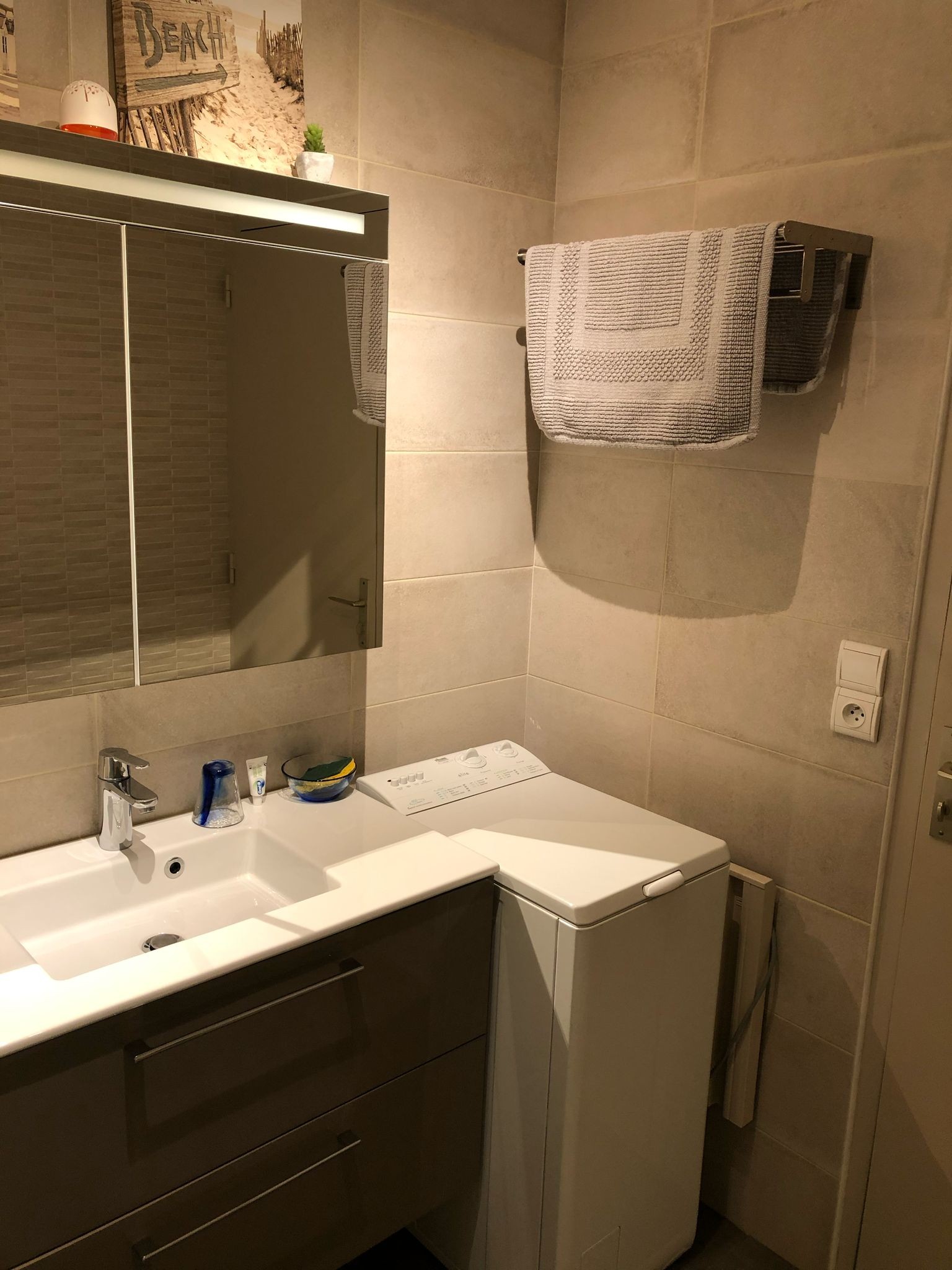 Salle d'eau avec douche grande dimension, meuble vasque, radiateur sèche serviette, lave-linge.