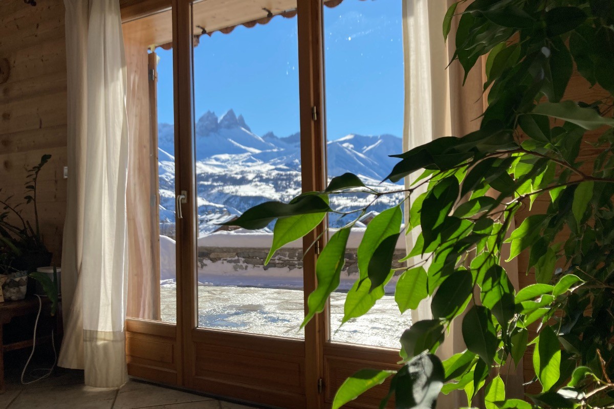 Salon avec télévision et poêle à bois, offrant une vue imprenable sur les montagnes et un accès direct à la terrasse.