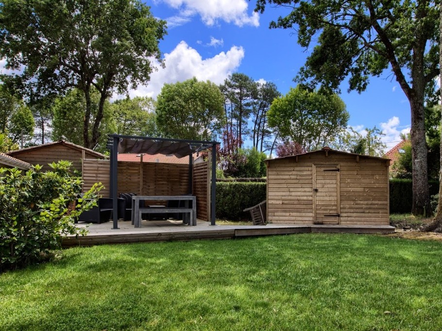terrasse en bois et salon de jardin sous les chênes.