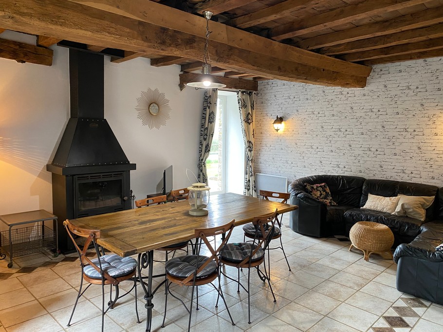 Grande pièce de vie au rez-de-chaussée avec espace cuisine toute aménagée et son mini bar, espace séjour, espace (vrai) bureau, et espace salon avec canapé en cuir, poêle à bois et TV.