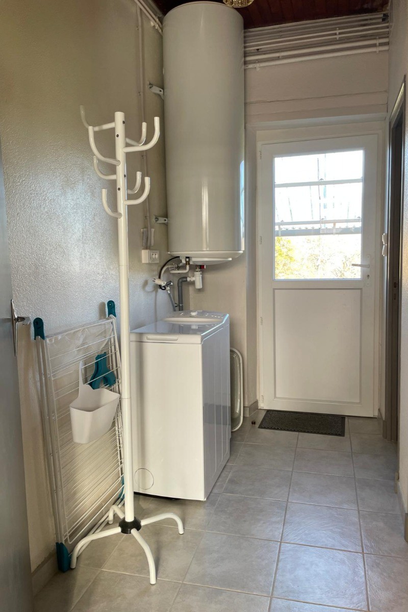 Couloir pratique avec machine à laver et porte donnant directement sur le jardin, idéal pour un séjour confortable