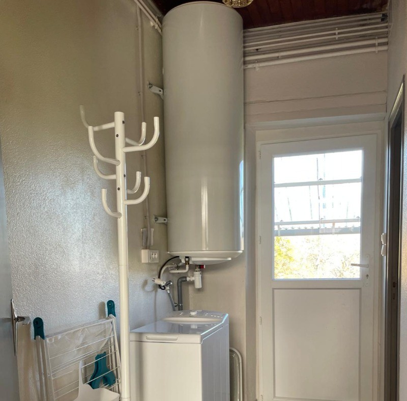 Couloir pratique avec machine à laver et porte donnant directement sur le jardin, idéal pour un séjour confortable