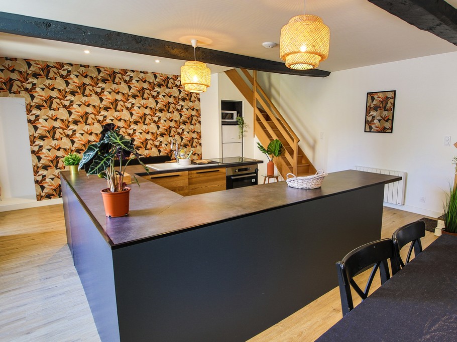 Pièce de vie au rez-de-chaussée avec sa cuisine ouverte, un coin séjour, un coin salon. 2 escaliers de part et d'autres desservent les 2 chambres.