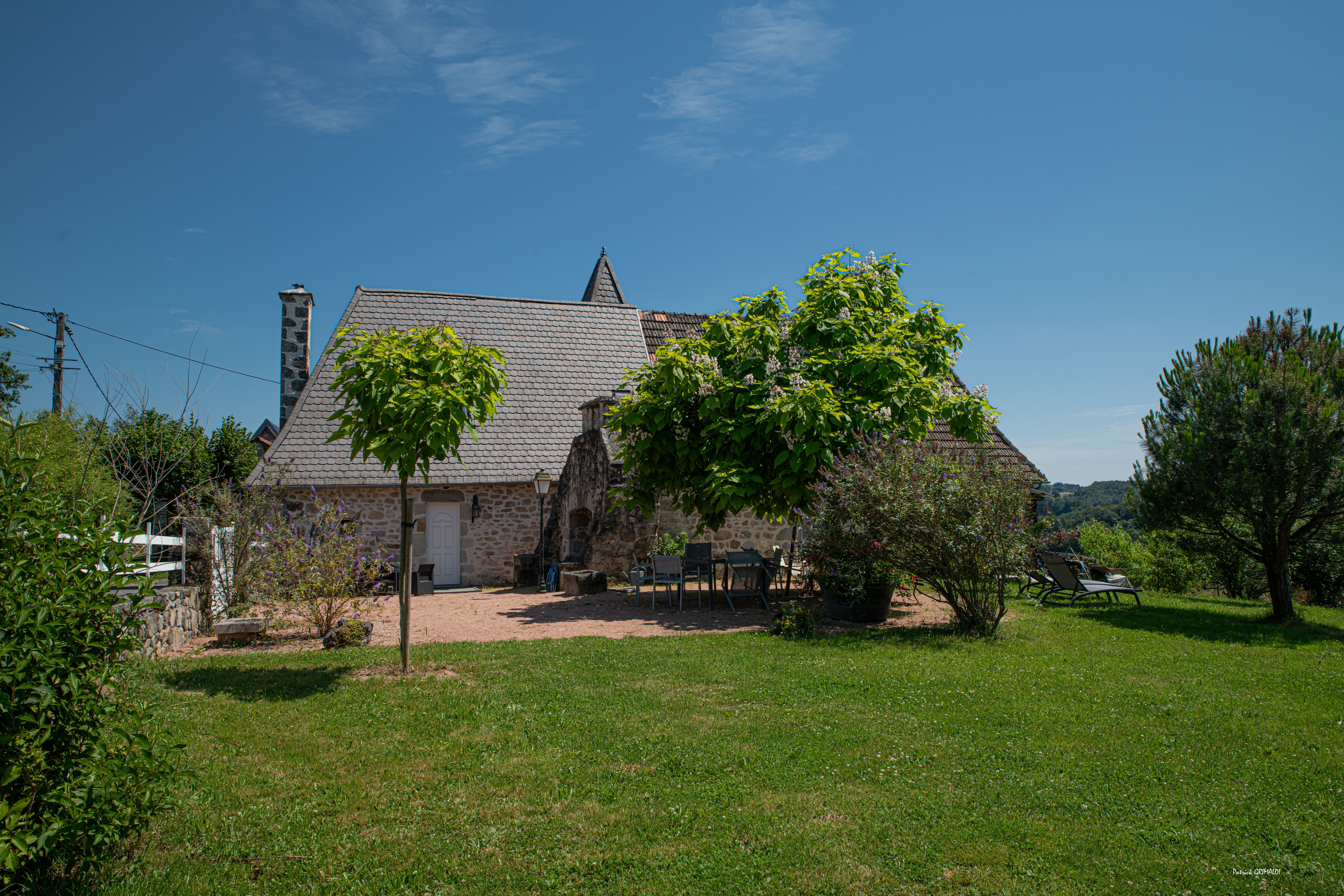 Terrasse du gîte avec barbecue, transats et salon de jardin face à la nature